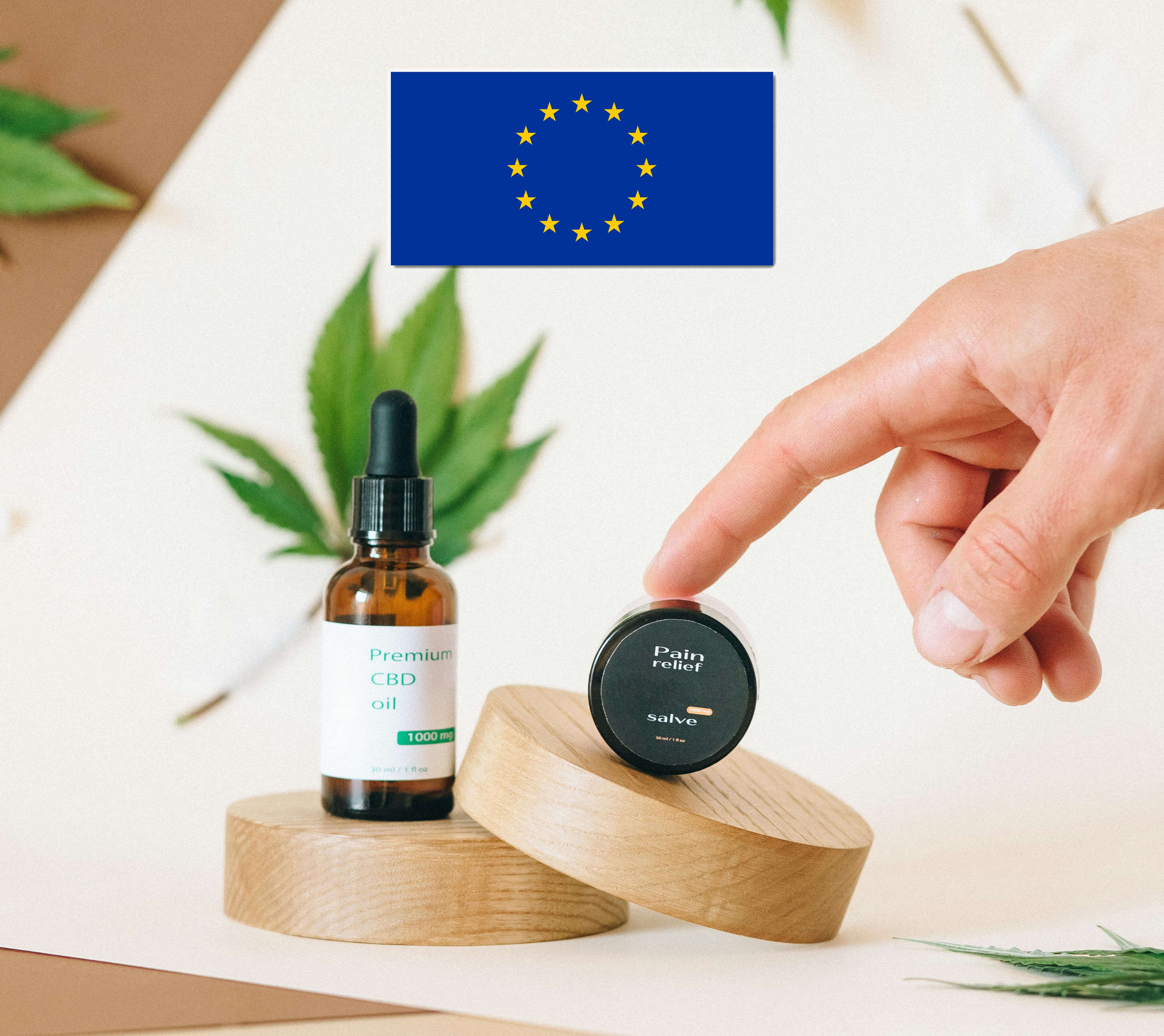 bottle of cbd oil and small container of salve and the european flag above them